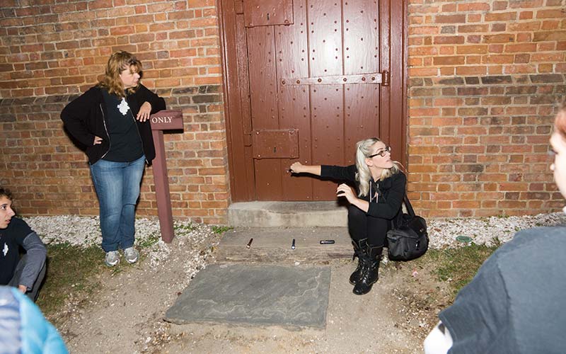 Colonial Ghost Tour guide knocking on a door in a haunted location