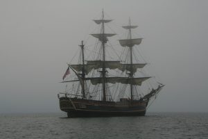 a dark schooner boat sits in a blanket of fog